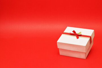Caja de regalo color blanco sobre un fondo rojo. Espacio para texto al lado izquierdo.