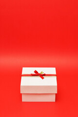 Caja de regalo color blanco sobre un fondo rojo. Espacio para texto en la parte superior.