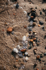 Small rocks on a sandy beach with water 