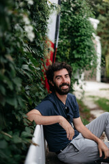 Handsome Latino man with a beard sitting on a bench