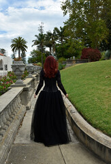 Obraz na płótnie Canvas portrait of pretty female model with red hair wearing glamorous gothic black lace ballgown. Posing in a fairytale castle location with staircases 