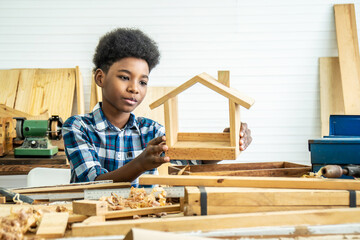 African-American boy carpenter looks at his own wooden house that helps his father happily do it