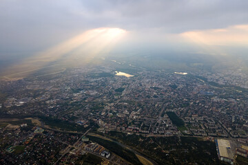Aerial view from high altitude of distant city covered with puffy cumulus clouds forming before rainstorm in evening. Airplane point of view of cloudy landscape