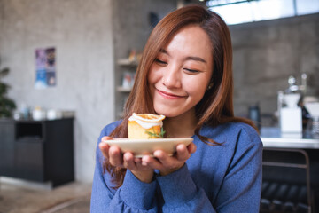 Portrait image of a young asian woman holding and eating a piece of lemon pound cake