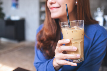 Closeup of a young asian woman holding and looking at a glass of iced coffee