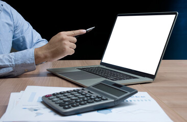 Businessman hand holding pen to display laptop and calculator on table