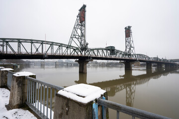 Hawthorne Bridge viewed from the west bank of the Willamette River in Portland, Oregon, in winter. The truss bridge is the oldest vertical-lift bridge in operation in the United States.