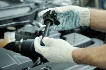 Automotive spare parts. Ignition coil close-up. An auto mechanic inspects a new ignition coil...