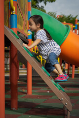 Fototapeta premium Little girl playing at the playground. Climbing and active.
