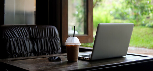 Laptop computer, coffee cup and smart phone on wooden table at coffee shop.