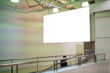 Blank large horizontal poster in public places. A mockup billboard near escalator in a shopping mall