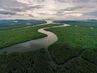 Aerial Drone footage flying over mangroves and lush rainforest in Phangnga bay Thailand The view is of mountainous islands and dramatic orange sunrise over the ocean