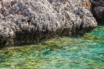 Emerald sea water and natural rocky seashore. Summer vacation and coastal nature concept