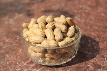 Bunch of unpeeled peanuts on a glass bowl