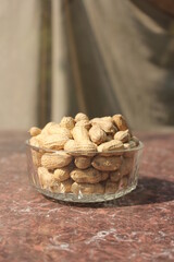 Bunch of unpeeled peanuts on a glass bowl