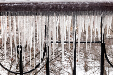 Ice icicles hanging from the iron fence of the balcony, a natural phenomenon. 