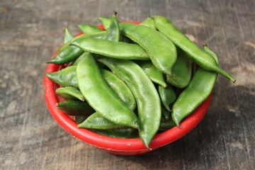 A bunch of green beans overloading on the bowl