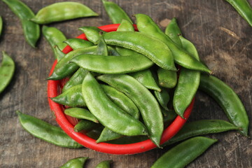 A bunch of green beans overloading on the bowl