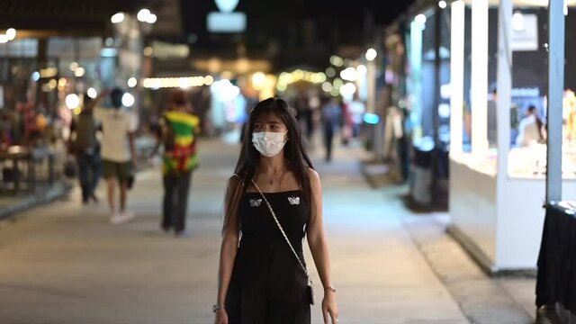beautiful Asian model walking towards camera in face mask during outbreak of omicron infectious virus 