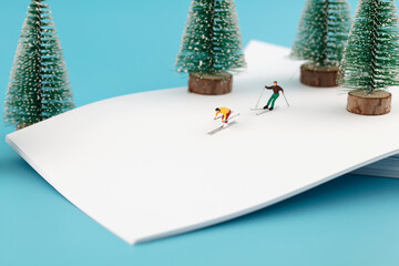 Skiers on a white paper in a miniature world