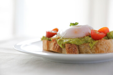 Poached eggs with avocado on toast in white background
