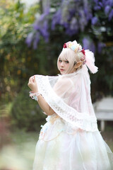 Beautiful young woman with white lolita dress with flowers garden Japanese fashion