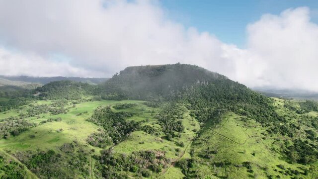 Drone shot of clouds and mist hanging over green Australian landscape with gumtrees