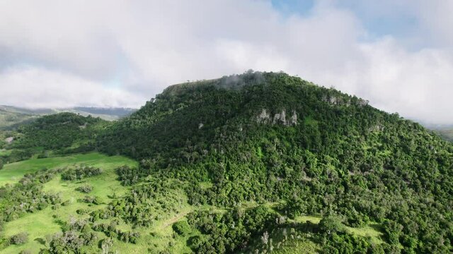 Push in drone shot of clouds hanging over green Australian mountain landscape with gumtrees