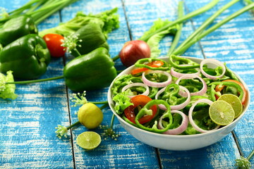 Bowl of fresh vegetable salad on a rustic kitchen table background.
