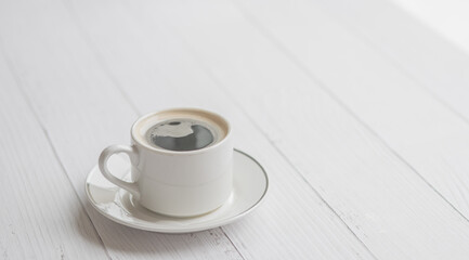 Cup of coffee on a white wooden table with copy space for text
