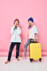 Portrait of a girl and a boy with a yellow suitcase in his hands studio posing