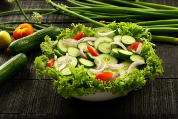 Fresh green cucumber salad, garnished with tomatoes, onions,herbs.