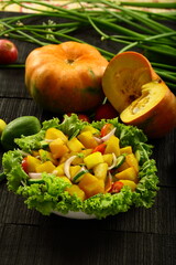 Healthy vegan diet foods- homemade pumpkin salad garnished with onions, tomatoes, capsicum and herbs.