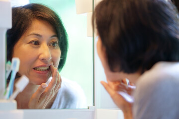 鏡を見て歯を気にする中年女性