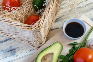 Vegetables on the table and in a basket, tomatoes, cucumbers, avocado, garlic and olive oil, vegetarianism, healthy eating