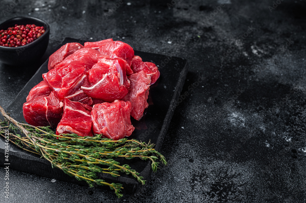 Wall mural raw diced red beef meat for goulash on marble board. black background. top view. copy space