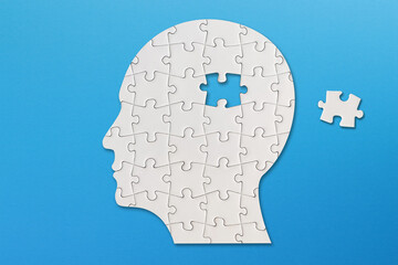 Brain shaped white jigsaw puzzle on blue background, a missing piece of the brain puzzle, mental...