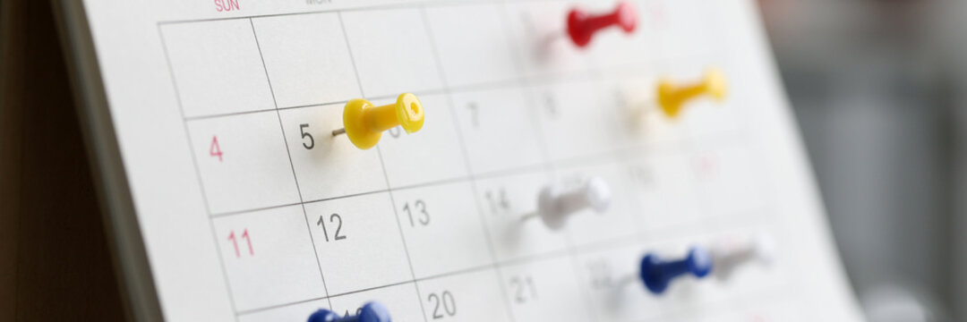 Various color thumb tack pins on calendar as reminder