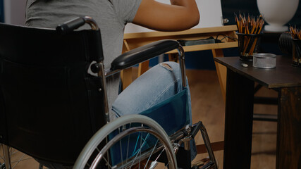 Fototapeta premium Close up of african american woman in wheelchair drawing vase for fine art concept at studio. Black person with disability working on authentic masterpiece with professional tools