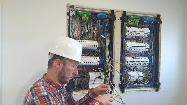 Electrical engineer preparing wiring for circuit panel inside a house - static view