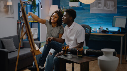 Couple of african american ethnicity working on art masterpiece in workshop space. Black young man and woman designing artistic vase drawing for innovative craft concept. Creative people