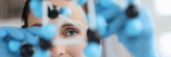 Scientist looks at model of mockup made of molecules closeup