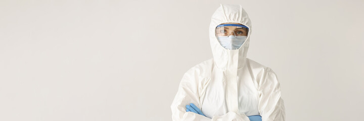 Woman doctor or scientist stands in protective suit, mask and glasses with folded arms on white background © megaflopp