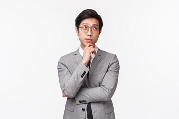 Waist-up portrait of smart and creative young asian male entrepreneur in grey suit, making plan,...