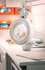 Examination laboratory setting featuring a magnifying lamp, disposable gloves and PPE and a selection of other lab equipment.