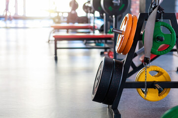 Close up of multicolored weight plates on the bar of gym. Copy space. Concept of bodybuilding and fitness