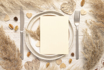 Wedding table place with blank card near dried pampas grass and hearts top view, mockup