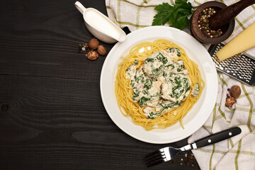Portion of delicious meatballs with spinach in a creamy sauce and pasta on wooden background