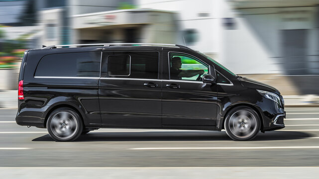 Mercedes-Benz Vito Tourer 119 CDI in motion on the city road on high speed. Black light commercial vehicle is driving on the highway, side view