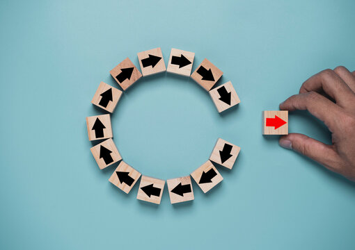 Disruption and technology transformation concept , Hand move out red arrow on wooden block cube move out from circle black arrow on blue background.
